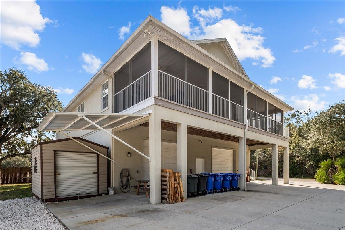 736-8 Kings Estate Road St. Augustine, FL 32086 - Photo 5 of 40 Rear view of property featuring an attached garage, a sunroom, concrete driveway, and a shed