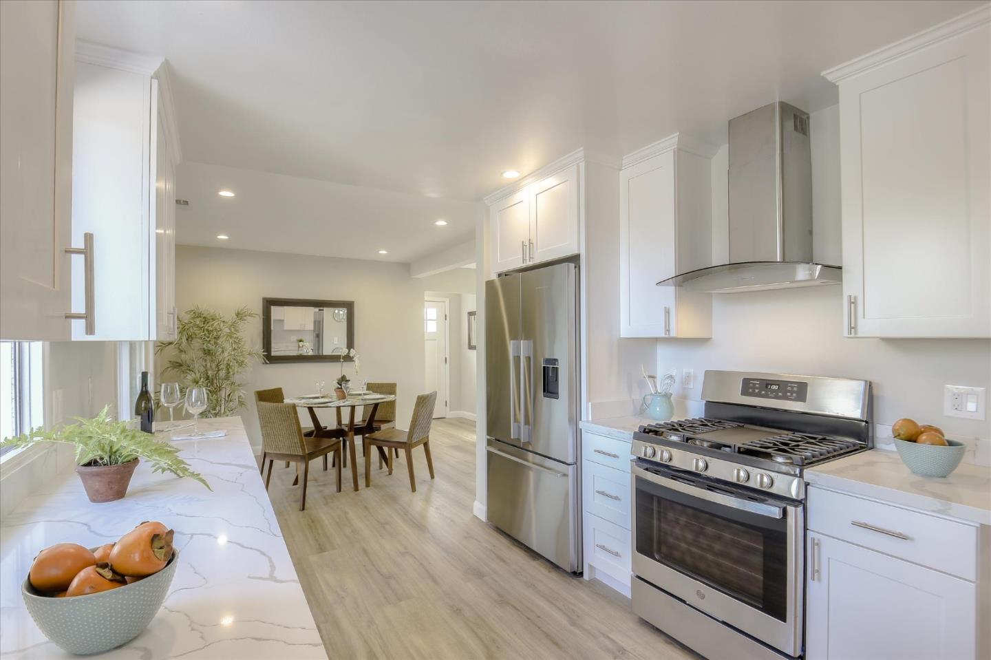 504 Arguello Boulevard Pacifica, CA 94044 - Photo 12 of 42 a kitchen with stainless steel appliances granite countertop a stove a refrigerator a sink a dining table and chairs with wooden floor