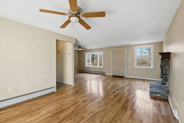 a view of empty room with wooden floor and fan
