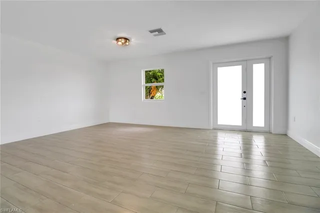 a view of an empty room with wooden floor and windows
