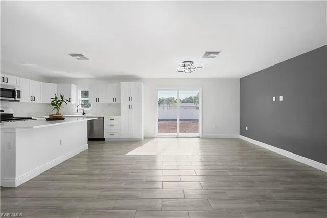 an empty room with wooden floor ceiling fan and windows