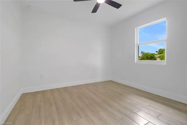 an empty room with windows and ceiling fan