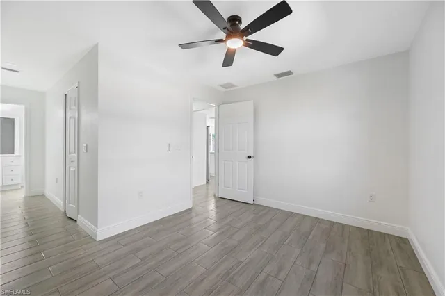 an empty room with ceiling fan and window