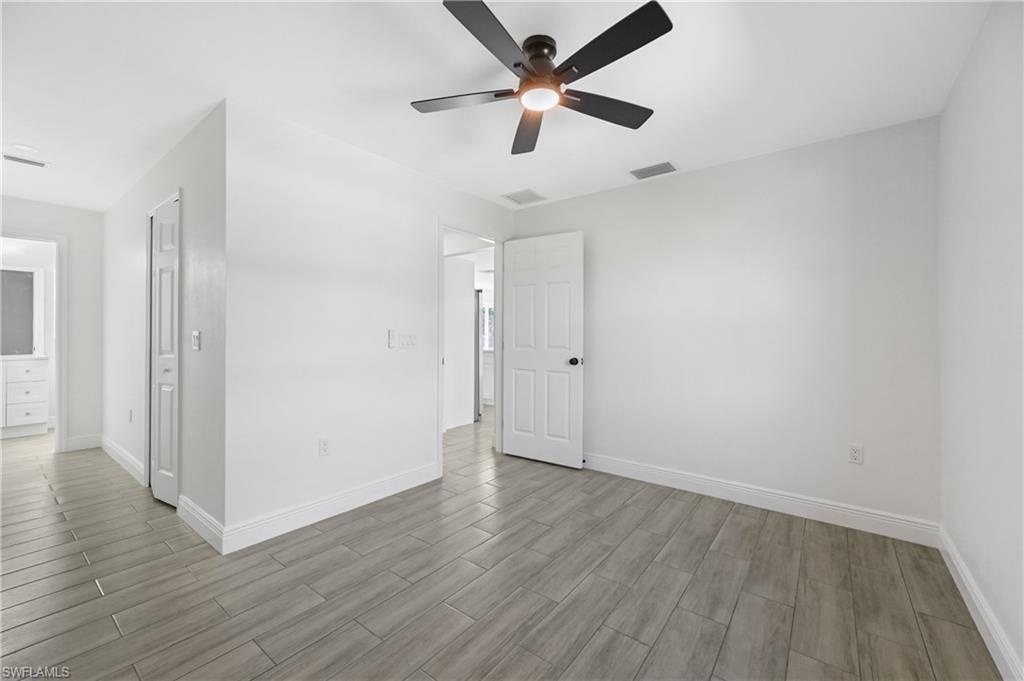 4448 18th Avenue Southwest Naples, FL 34116 - Photo 21 of 40 an empty room with wooden floor ceiling fan and windows