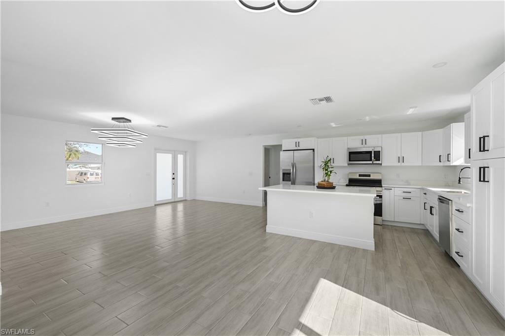 4448 18th Avenue Southwest Naples, FL 34116 - Photo 40 of 40 Kitchen with white cabinets, open floor plan, wood tiled floors, and stainless steel appliances