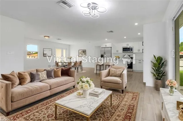 a living room with furniture a rug kitchen view and a chandelier