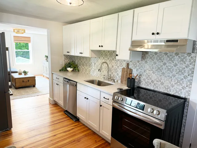 a kitchen with granite countertop a stove and white cabinets
