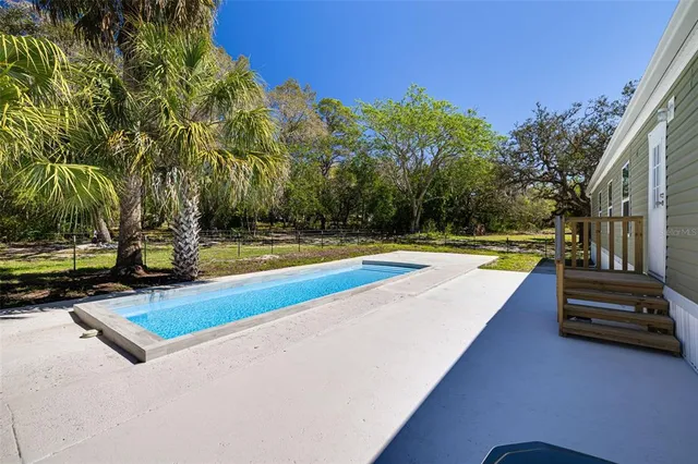 a view of swimming pool with chairs and trees