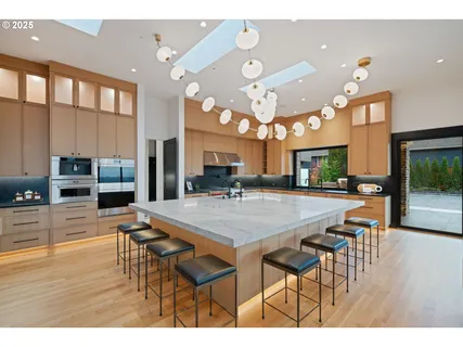 a dining hall with stainless steel appliances kitchen island granite countertop a table chairs and a view of living room