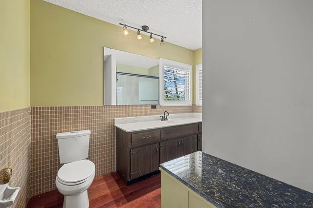 a bathroom with a granite countertop toilet a sink and a mirror