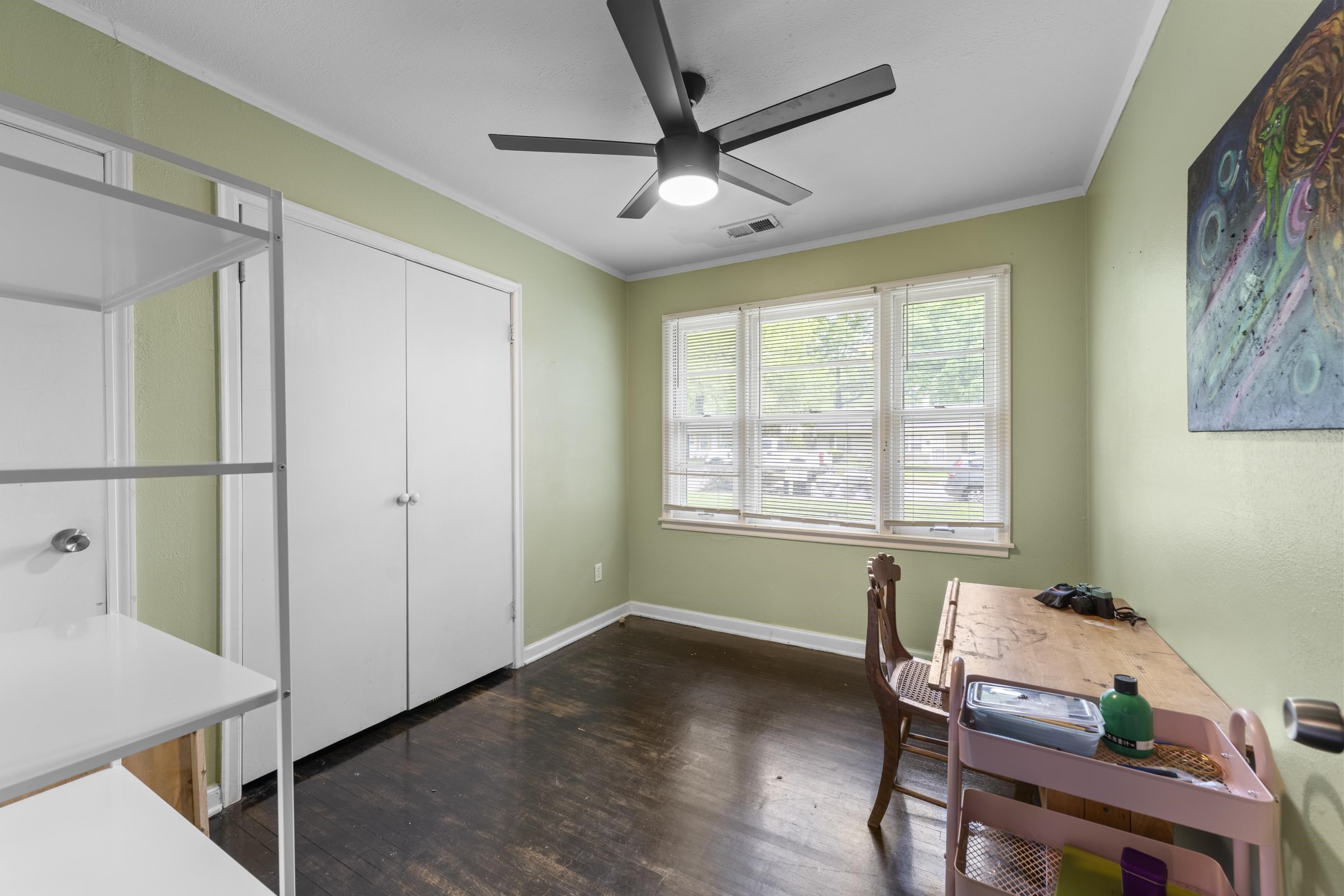 1343 Dearing Road Memphis, TN 38117 - Photo 15 of 19 Room featuring three large windows, a ceiling fan with integrated lighting, bi-fold closet doors, and wood-finish flooring