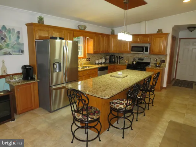 a kitchen with stainless steel appliances granite countertop a refrigerator a stove a sink a table and chairs