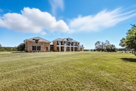 a view of a big house with a big yard and large trees
