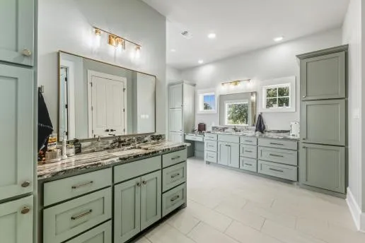 a bathroom with a granite countertop double vanity sink a mirror a vanity and shower
