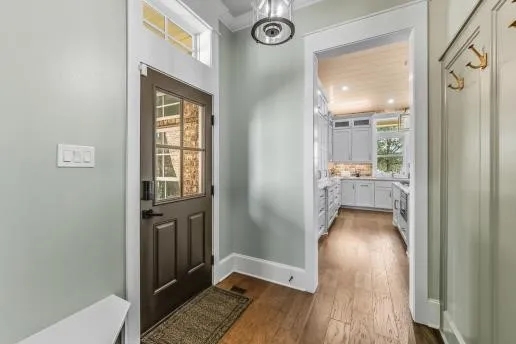 a view of a hallway with wooden floor and a bathroom