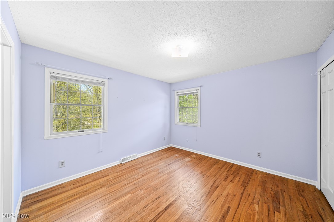 3325 Frantz Road Medina, OH 44256 - Photo 22 of 40 Unfurnished bedroom with visible vents, a closet, wood finished floors, baseboards, and a textured ceiling