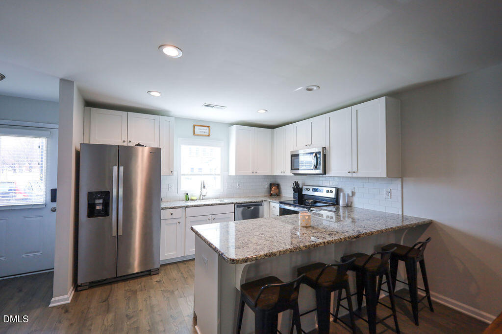 230 South Raleigh Street Angier, NC 27501 - Photo 10 of 38 a kitchen with stainless steel appliances granite countertop a dining table chairs refrigerator and cabinets