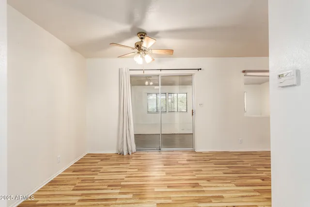 a view of empty room with wooden floor and fan