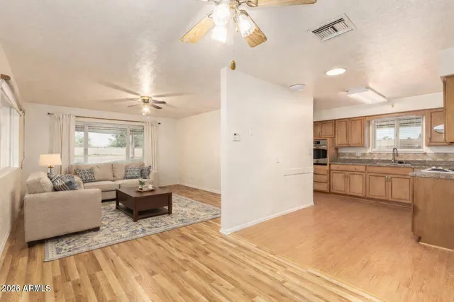 a living room with couches and kitchen view with wooden floor