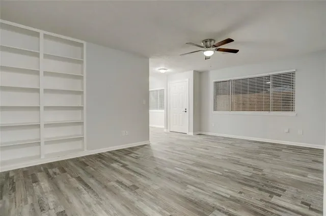 a view of an empty room with a window and a kitchen