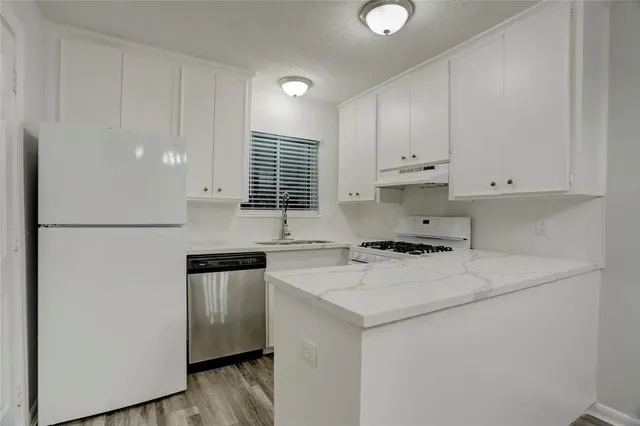 a kitchen with stainless steel appliances granite countertop a sink a stove a refrigerator a center island cabinets and a window