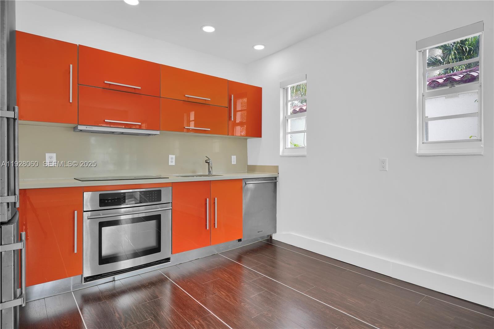 1457 Meridian Avenue, Unit 204 Miami Beach, FL 33139 - Photo 6 of 20 an empty room with wooden floor and kitchen with windows
