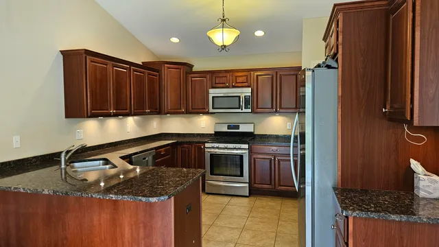 a kitchen with granite countertop a sink stainless steel appliances and cabinets