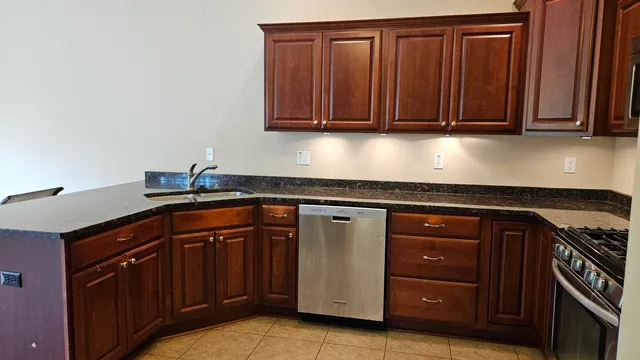 a kitchen with granite countertop a sink cabinets and stainless steel appliances