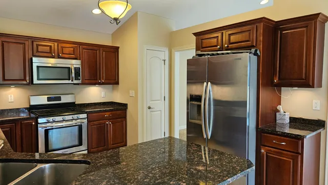 a kitchen with granite countertop a refrigerator stove and microwave