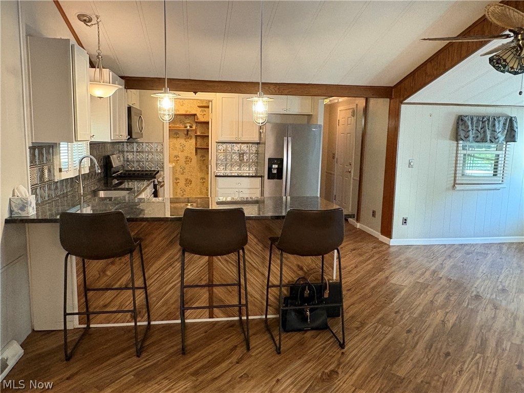 8701 Mayfield Road, Unit 148 Chesterland, OH 44026 - Photo 3 of 22 Kitchen featuring a breakfast bar with wood-finish paneling, dark countertops, and pendant lighting