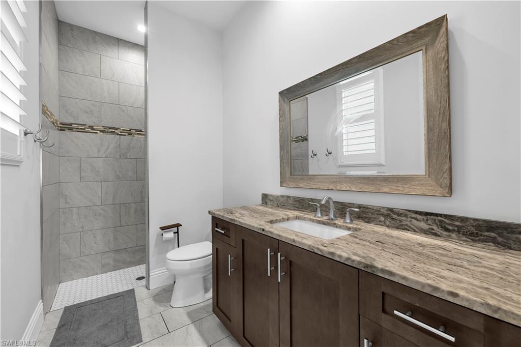 11141 Palmetto Ridge Drive Naples, FL 34110 - Photo 15 of 31 a bathroom with a granite countertop sink a toilet and a mirror