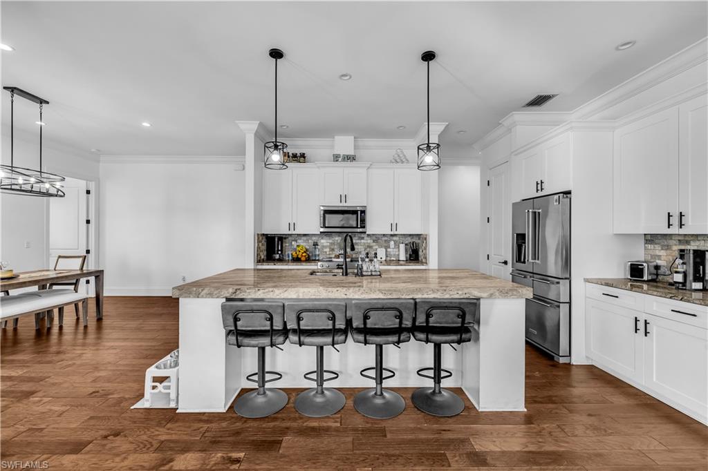 11141 Palmetto Ridge Drive Naples, FL 34110 - Photo 17 of 31 a view of a kitchen with kitchen island stainless steel appliances refrigerator stove dining table and chairs