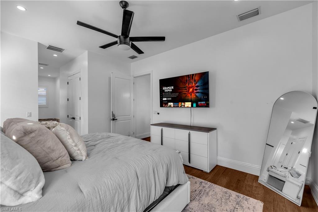 11141 Palmetto Ridge Drive Naples, FL 34110 - Photo 8 of 31 a bedroom with a bed a mirror on the wall and a flat screen tv