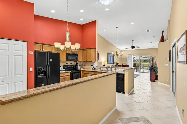 a kitchen with stainless steel appliances granite countertop a refrigerator a stove a sink cabinets and a dining table