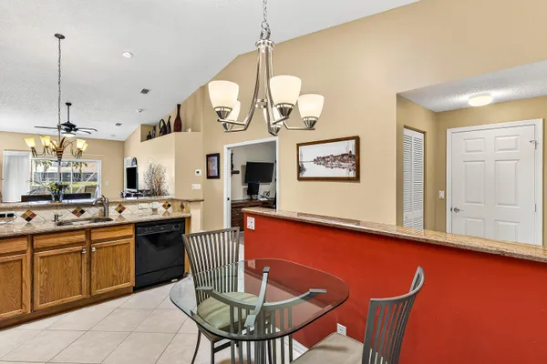 a kitchen with stainless steel appliances a refrigerator a sink a stove top oven a dining table and chairs