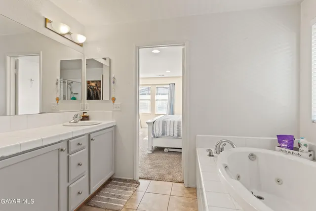 a spacious bathroom with a tub sink and mirror