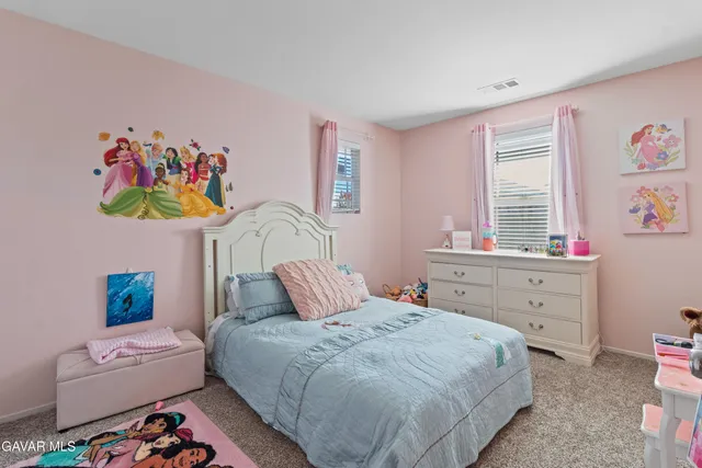a bedroom with a bed a dresser and painting on the wall