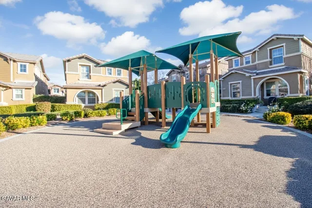 a view of a white house with a swimming pool and lawn chairs under an umbrella