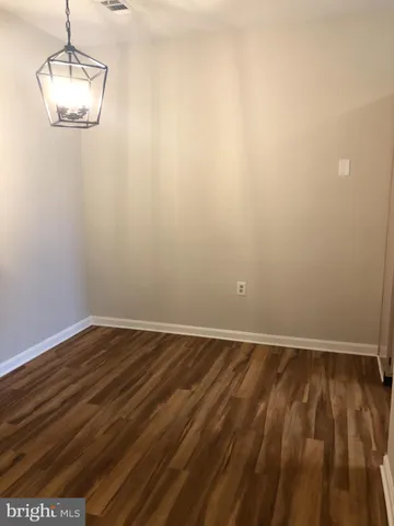 a view of an empty room with wooden floor and chandelier