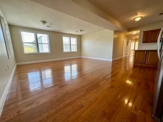 a view of empty room with wooden floor and fan