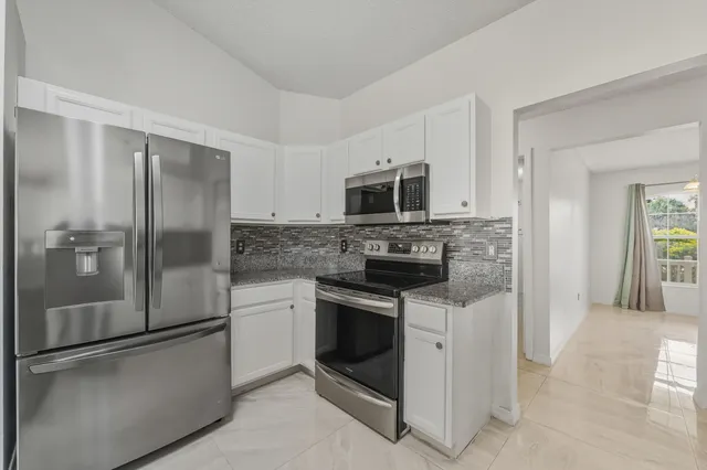 a kitchen with stainless steel appliances granite countertop a refrigerator and a stove top oven