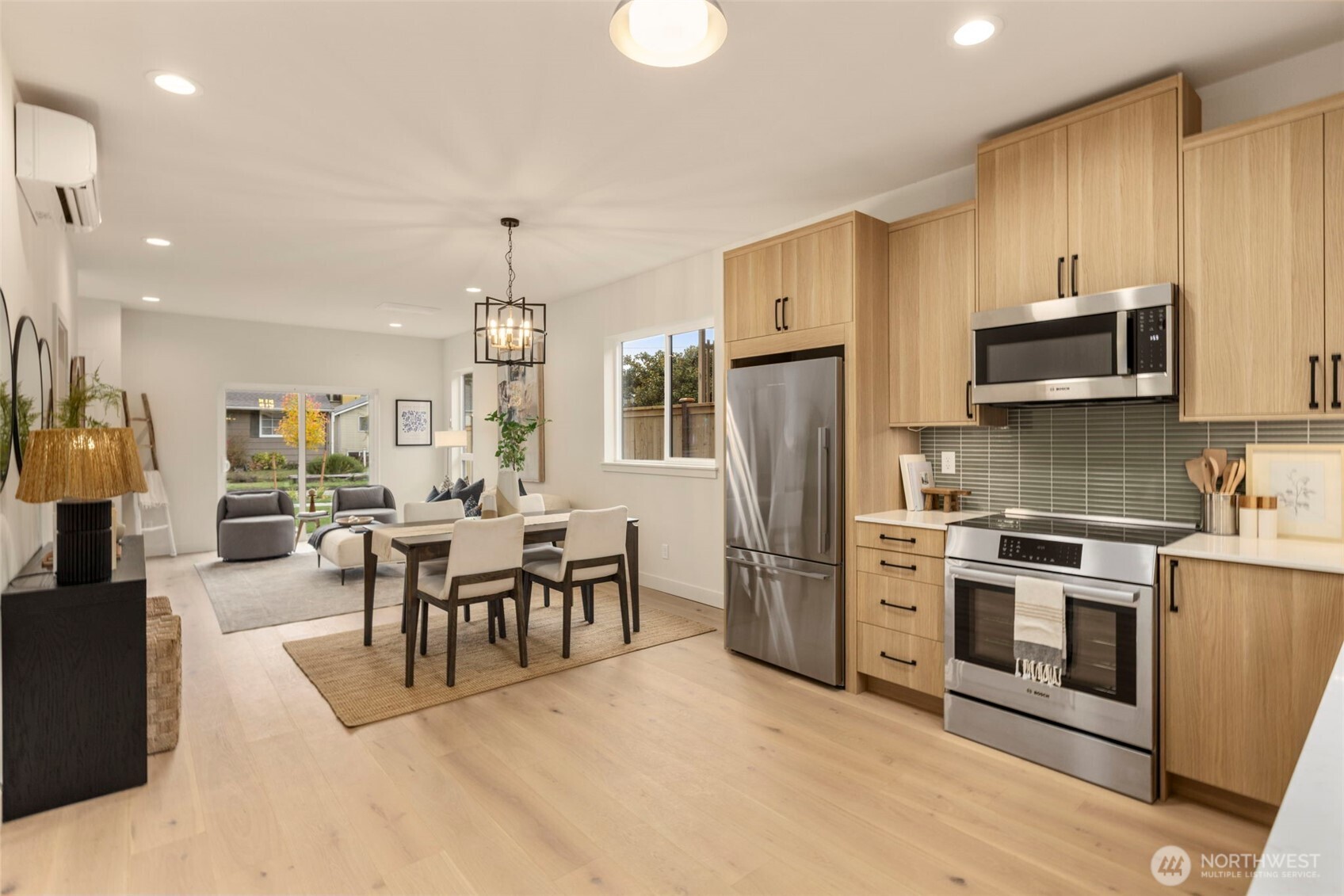 3404 33rd Avenue West Seattle, WA 98199 - Photo 15 of 29 a kitchen with stainless steel appliances kitchen island granite countertop a refrigerator a stove a sink a dining table and chairs with wooden floor