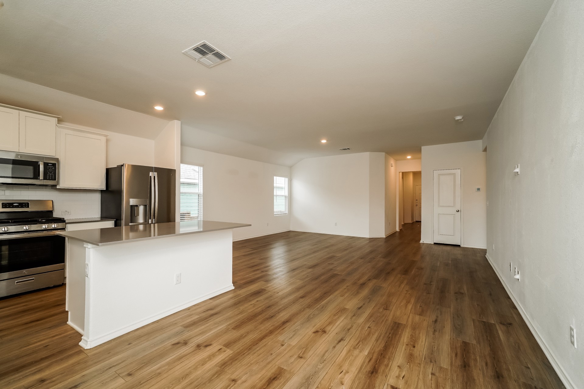 341 Madrid Kyle, TX 78640 - Photo 7 of 27 A seamless flow connects the modern kitchen, featuring stainless steel appliances and an island, to the spacious living area.