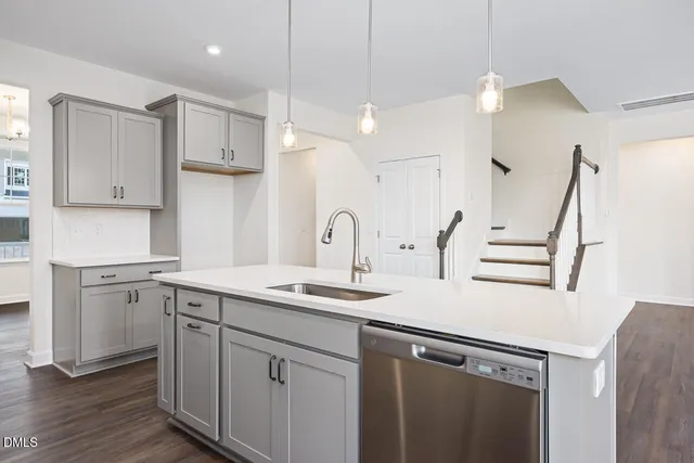 a kitchen with a sink dishwasher and white cabinets with wooden floor