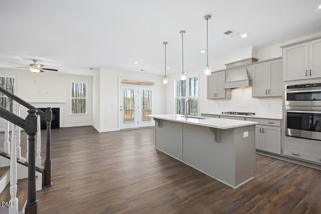 a large kitchen with stainless steel appliances a large counter top a stove a refrigerator and a view of living room