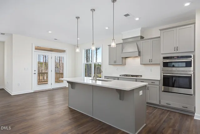 a kitchen with stainless steel appliances granite countertop a sink a stove and a wooden floors