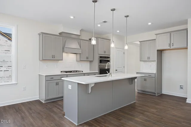 a kitchen with stainless steel appliances white cabinets a sink a stove a refrigerator and island