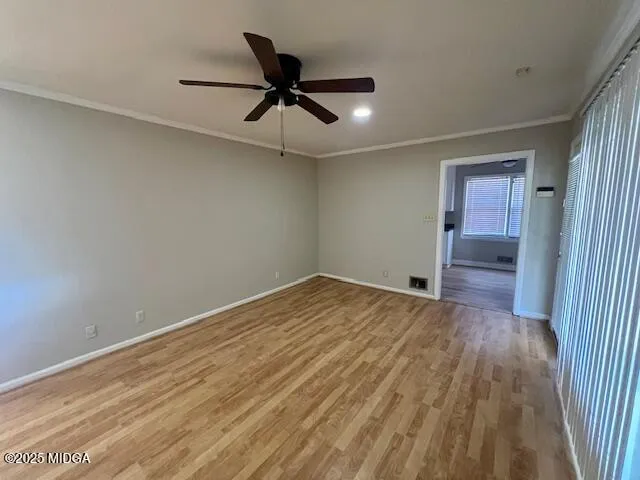 a view of empty room with wooden floor and fan