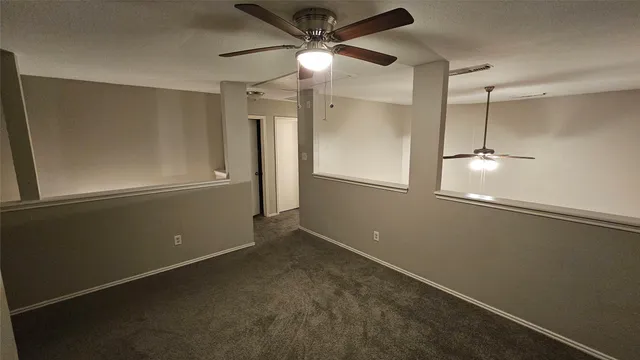 a view of a room with wooden floor and a ceiling fan