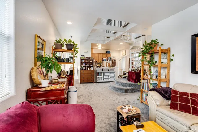 a living room with furniture kitchen view and a chandelier